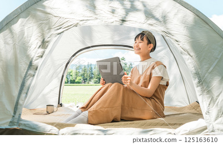 Girl using a tablet in a tent at a campsite/leisure facility 125163610