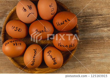 Investment concepts represented with eggs on a wooden plate Investment concepts represented with eggs on a wooden plate 125163915