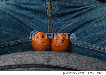 Funny eggs with faces placed on a person's lap 125163920