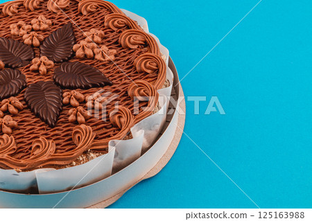 Delicious chocolate cake with decorative frosting on blue background Delicious chocolate cake with decorative frosting on blue background 125163988