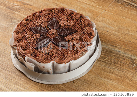 Delicious chocolate cake decorated with chocolate leaves on wooden table Delicious chocolate cake decorated with chocolate leaves on wooden table 125163989