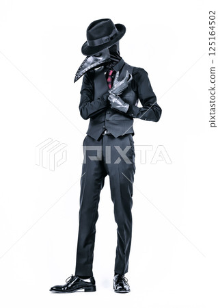 A plague doctor in a suit wearing a plague mask and adjusting gloves 125164502