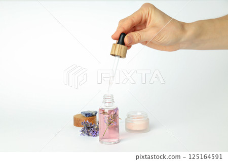 Cosmetic jar and serum bottle, lavender and hand on white background 125164591