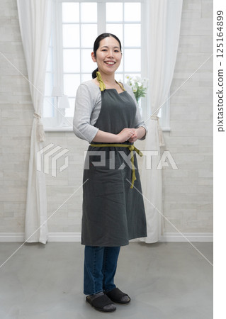 A woman with a smile wearing an apron A woman with a smile wearing an apron 125164899