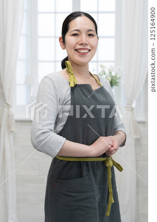 A woman with a smile wearing an apron 125164900