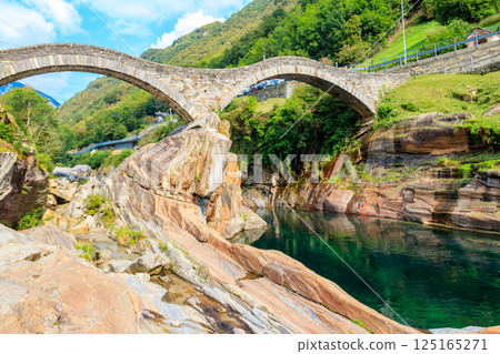 Ancient double arch stone Roman bridge (Ponte dei Salti) over the clear water of the Verzasca river in Lavertezzo ,Verzasca Valley, Ticino Canton, Switzerland 125165271