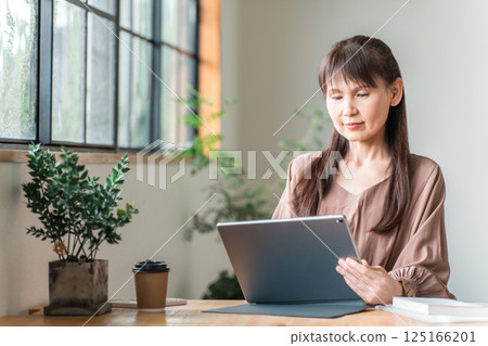 在咖啡館從事遠距辦公/行動工作的亞洲中年女性 125166201