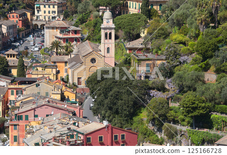 Portofino, Italy - 07 April 2025. Tourism in Italy. Traditional buildings, church, plant and trees in bay of Liguria. Background for design. 125166728