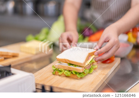 Hands Assembling a Fresh Sandwich on Wooden Cutting Board Hands Assembling a Fresh Sandwich on Wooden Cutting Board 125166846