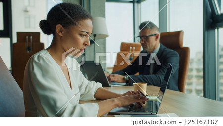 Focused businesswoman working on laptop in office 125167187