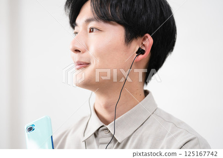 Young man listening to music with wired earphones Young man listening to music with wired earphones 125167742