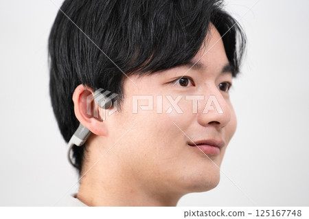 Young man listening to music with wireless earphones 125167748