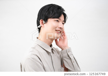 Young man listening to music with wireless earphones 125167749