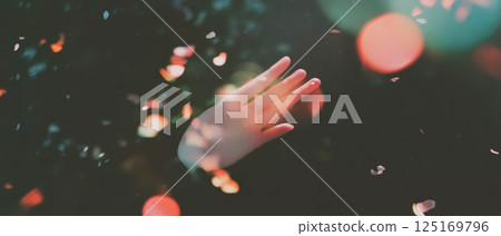 A hand extends outward, surrounded by soft light leaks and a vintage texture effect. 125169796