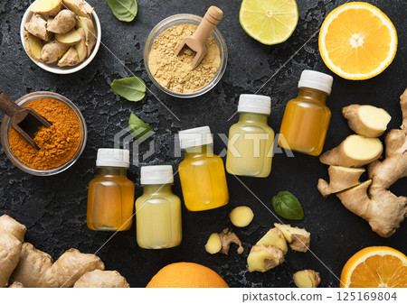Bottles of immune turmeric ginger energy shot drink with fresh raw ginger roots and oranges fruits Bottles of immune turmeric ginger energy shot drink with fresh raw ginger roots and oranges fruits 125169804