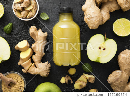 Bottle of energy shot immune drink with ginger and green apples with limes on black background. Bottle of energy shot immune drink with ginger and green apples with limes on black background. 125169854