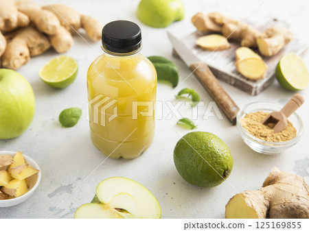 Bottle of energy shot immune drink with ginger and green apples with limes on light background. 125169855