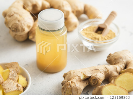 Ginger and orange energy shot immune drink with fresh raw ginger root on light background.Macro. 125169863