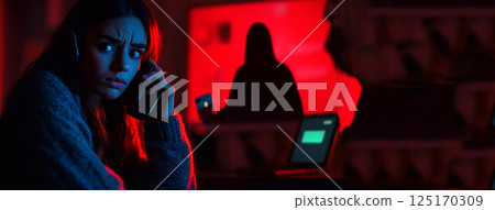 A young woman at night looking at her card with concern, symbolizing online identity theft and financial fraud. The dark atmosphere and glowing screen highlight the risks of cyber scams A young woman at night looking at her card with concern, symbolizing online identity theft and financial fraud. The dark atmosphere and glowing screen highlight the risks of cyber scams 125170309