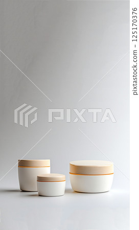 Three pastel cosmetic cream jars arranged vertically on a white background. Minimal skincare and beauty concept for vertical story or reel format 125170376