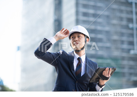 A man in a suit holding a tablet at a construction site A man in a suit holding a tablet at a construction site 125170586