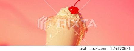 Creamy milkshake with fluffy whipped cream and a cherry, served in a frosty glass. 125170686