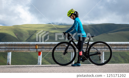 Cyclist with road bike on grassland mountain top trail Cyclist with road bike on grassland mountain top trail 125171202