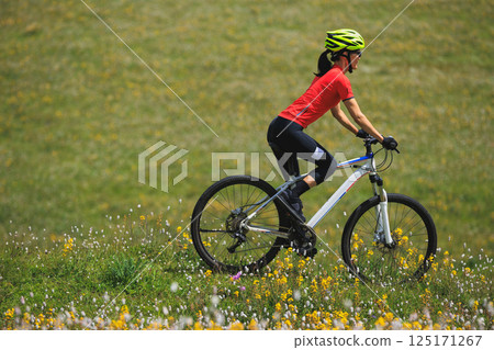 Fitness aisan woman riding mountain bike on beautiful flowering grassland mountain top 125171267
