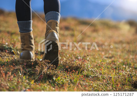 Hiker legs wearing  leather boots hiking on high altitude mountain top 125171287