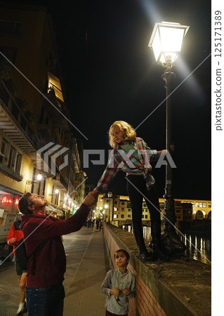 Nighttime Playful Moment Under Streetlight on Bridge 125171389