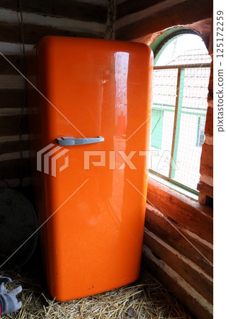 This is a stunning Vintage Orange Refrigerator beautifully set within a Rustic Setting 125172259