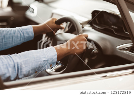 Driving Car. Unrecognizable Afro Driver Man Holding Steering Wheel Driving Sitting In New Luxury Auto. Cropped, Selective Focus Driving Car. Unrecognizable Afro Driver Man Holding Steering Wheel Driving Sitting In New Luxury Auto. Cropped, Selective Focus 125172819