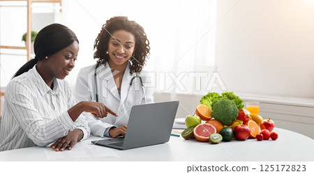 African women dietician and patient looking at laptop screen at dietologist cabinet, copy space African women dietician and patient looking at laptop screen at dietologist cabinet, copy space 125172823