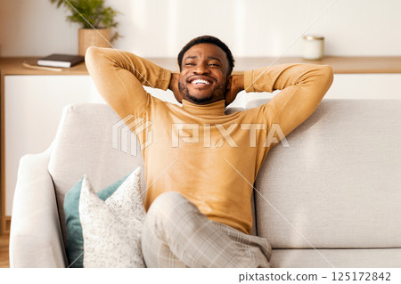 Relaxed African American Man Resting Sitting On Couch Holding Hands Behind Head At Home. Enjoying Weekend. Free Space 125172842