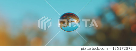 A big droplet reflects a blurred landscape with soft hues on a bright background. A big droplet reflects a blurred landscape with soft hues on a bright background. 125172872