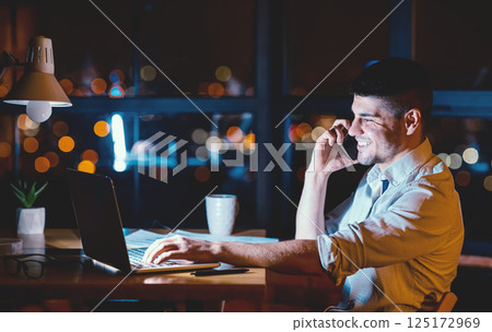 Male Entrepreneur Talking On Cellphone Working On Laptop Overnight In Modern Office. Business Lifestyle. Copy Space 125172969