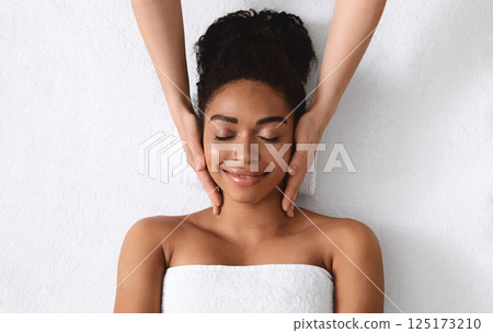 Top view of relaxed black young woman having facial massage over white background Top view of relaxed black young woman having facial massage over white background 125173210