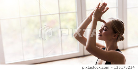 Portrait of peaceful girl practicing yoga at home, opening chakras, holding hands in namaste sign Portrait of peaceful girl practicing yoga at home, opening chakras, holding hands in namaste sign 125173234