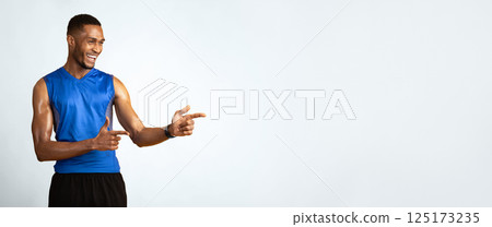 Great Promo. Happy black sportive guy pointing two index fingers aside at copy space over yellow studio background 125173235