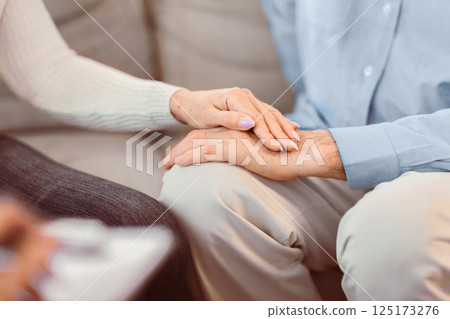 Psychotherapy. Close up of unrecognizable mature couple holding hands, caring elderly woman comforting her husband Psychotherapy. Close up of unrecognizable mature couple holding hands, caring elderly woman comforting her husband 125173276