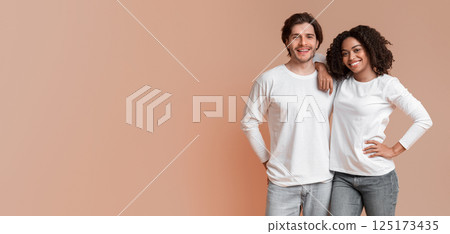 Portrait of happy interracial couple hugging and posing to camera, standing over yellow background with free space Portrait of happy interracial couple hugging and posing to camera, standing over yellow background with free space 125173435