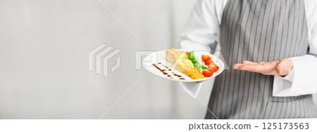 Unrecognizable Chef Holding Plate With Cooked Salmon Steak Serving Fish Dish In Restaurant Kitchen. Cropped, Selective Focus Unrecognizable Chef Holding Plate With Cooked Salmon Steak Serving Fish Dish In Restaurant Kitchen. Cropped, Selective Focus 125173563