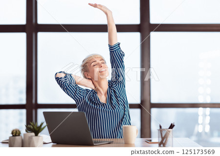 Female Entrepreneur At Laptop Stretching Hands Having Break Relaxing At Work Sitting In Modern Office. Selective Focus 125173569