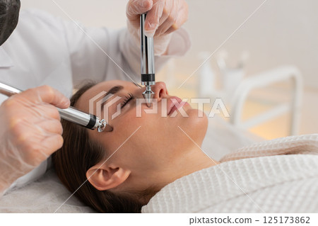 Beautician doctor makes woman micro currents face therapy using electrical impulses in spa salon Beautician doctor makes woman micro currents face therapy using electrical impulses in spa salon 125173862