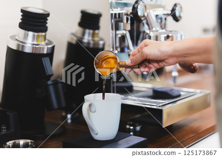 Woman barista pouring hot coffee intop white mug. 125173867