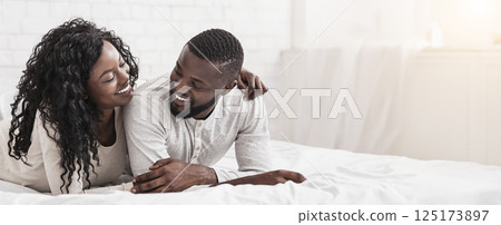 Romantic african american couple cuddling on bed at home, enjoying time together, closeup 125173897