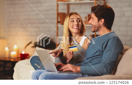 Happy Couple Shopping Online On Laptop And Paying With Credit Card Buying Things On Internet Sitting On Sofa At Home 125174026