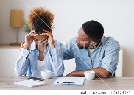 Afro Husband Comforting His Wife Crying On Family Or Adoption Counseling. Selective Focus 125174125