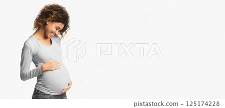 Afro woman feeling unity with unborn child, touching her belly, white background 125174228