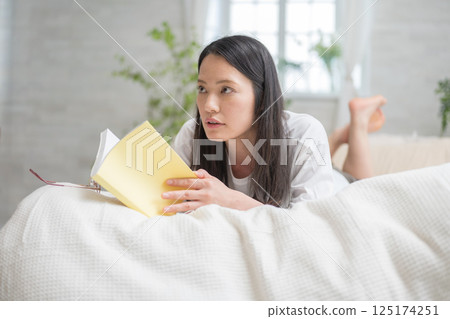 Beautiful woman reading in bed | Study | Hobby | Healthy living image | Well-being girl | Well-being 125174251
